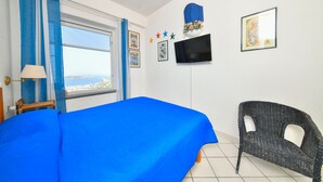 A bedroom with a bed, a chair, a TV, and a window with curtains. - Villa Bianca - A corner of paradise (Barano D'ischia)