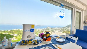 A table with a view of the sea, a blue sofa, and a water dispenser. - Villa Bianca - A corner of paradise (Barano D'ischia)