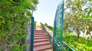 A staircase with red steps leading up to a building, surrounded by greenery and a metal gate. - Villa Bianca - A corner of paradise (Barano D'ischia)