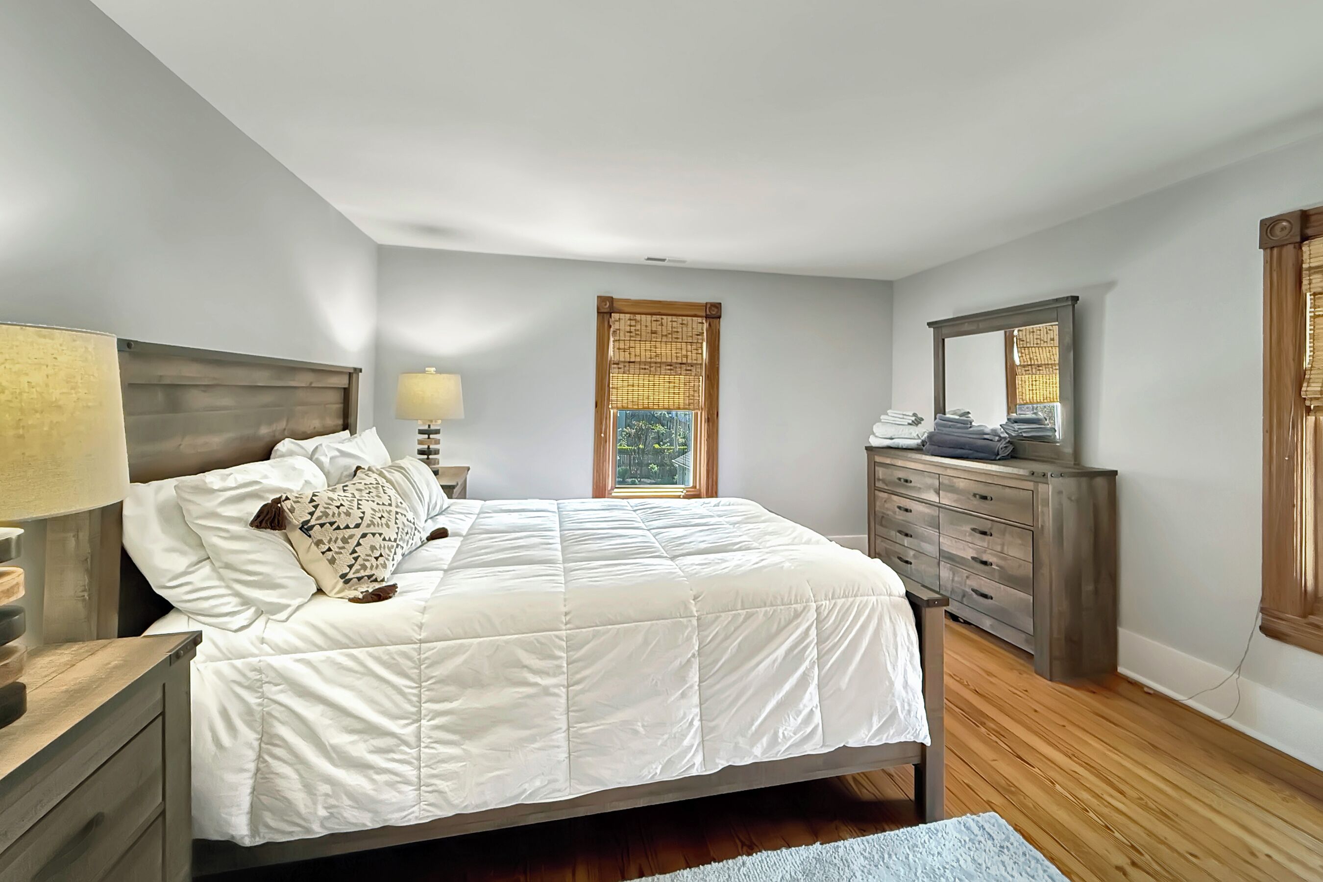 A bedroom with a bed, nightstand, dresser, and window with blinds.