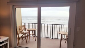 En balkong med utsikt över havet, möblerad med trästolar och ett litet bord.