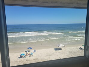 A beach view from inside a building, with the ocean and clear sky visible.