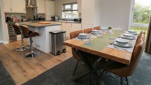 A modern kitchen with a dining area set for six. - Lily (Lifton)