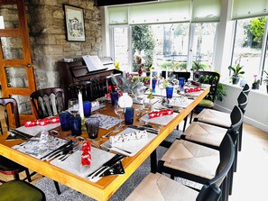 Un espace repas avec une longue table en bois dressée pour un repas, entourée de chaises.