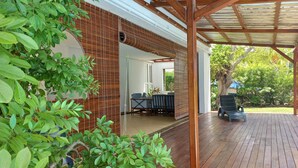 A covered outdoor area with a wooden deck, a brick wall, and a seating area with a table and chairs.