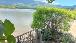 A stone wall with a metal gate, a lamp post, and a view of a lake with mountains in the background.