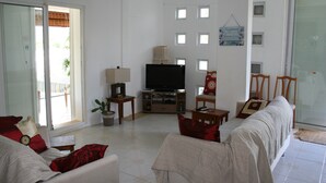 A living room with a sofa, a television, and a sliding glass door leading to an outdoor area.