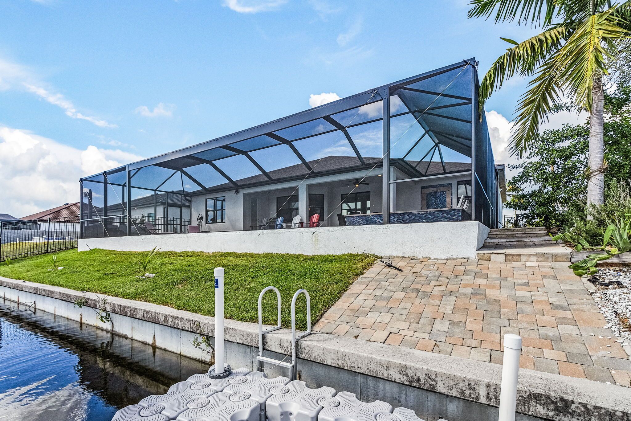 A modern house with a glass-enclosed patio, a swimming pool, and a brick pathway.