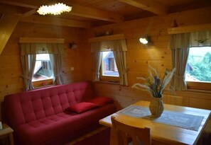 Una habitación acogedora con un sofá rojo, paredes de madera y una mesa con un jarrón.
