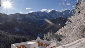 A snow-covered outdoor seating area with a view of snow-covered mountains in the background.