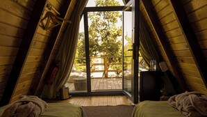 Ein gemütliches Schlafzimmer im Dachgeschoss mit zwei Betten, Holzboden und einer Glastür zum Balkon.