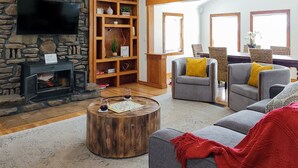 Ein gemütliches Wohnzimmer mit Kamin aus Stein, Holzböden und bequemen Sitzmöglichkeiten.