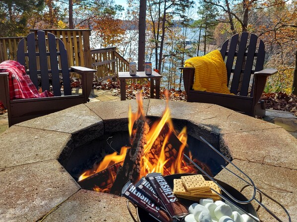 Ein Lagerfeuer mit Marshmallows und Schokoriegeln, umgeben von Adirondack-Stühlen mit Decken.