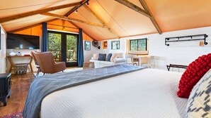 Um quarto espaçoso com uma cama grande, teto de madeira, escrivaninha e um sofá.