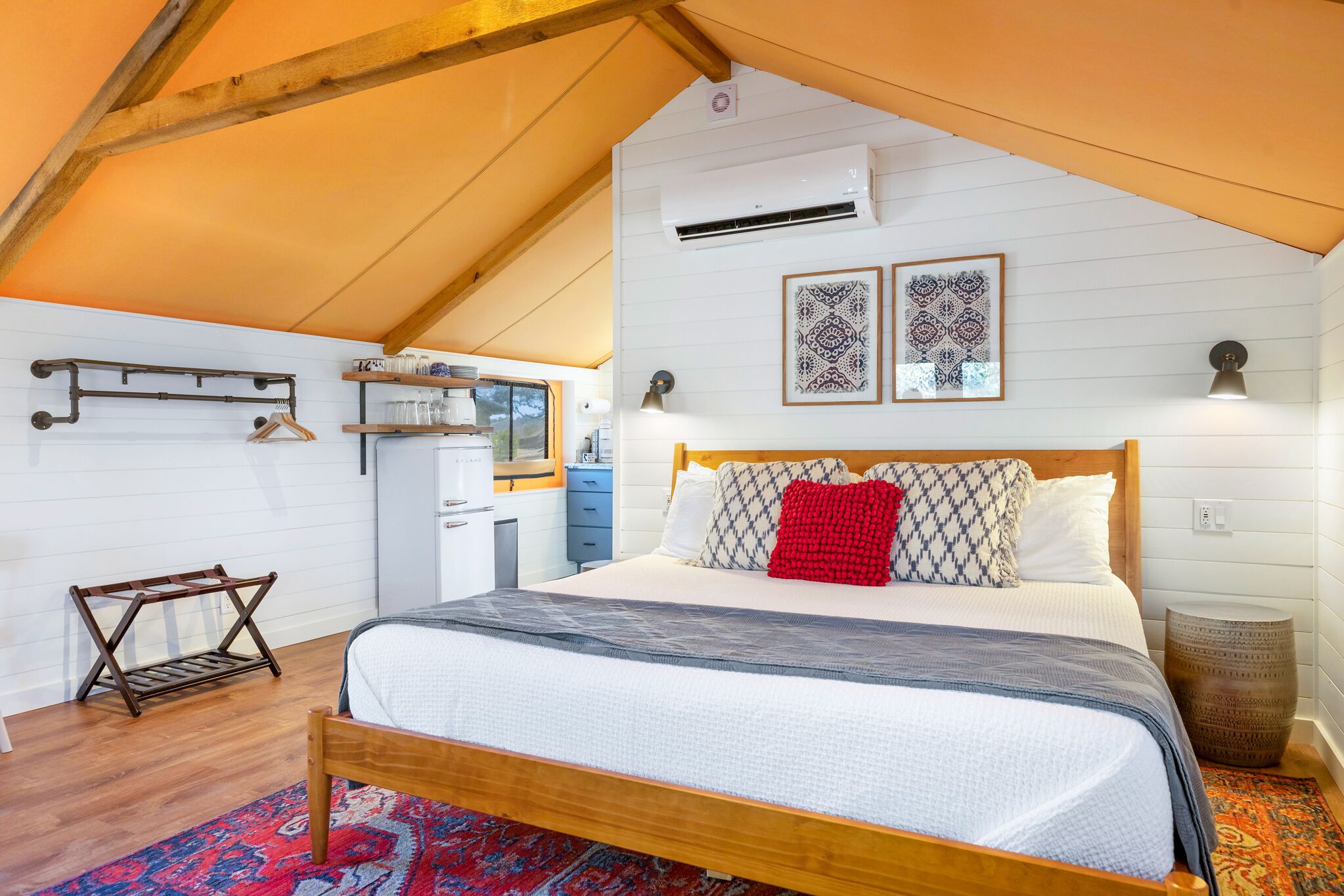 Un dormitorio con una cama de madera, paredes blancas y techo inclinado.