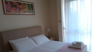 A hotel room with a large bed, a nightstand, a lamp, and a painting on the wall. - Le Barchette 2 - Piano Terra (Lecce)