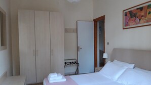 A hotel room with a bed, a wardrobe, a desk, and a bathroom visible through an open door. - Le Barchette 2 - Piano Terra (Lecce)