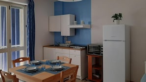 Una cocina compacta con comedor, refrigerador, microondas y horno pequeño.