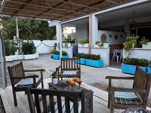 An outdoor patio area with wooden furniture, potted plants, and a table with glasses. - Le Barchette 6 - Piano Terra (Lecce)