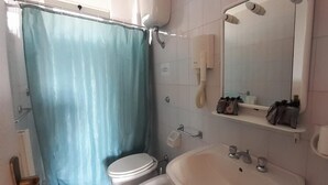 A bathroom with a toilet, sink, and shower area.