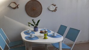 A round table with four chairs, a potted plant, and a coffee machine.