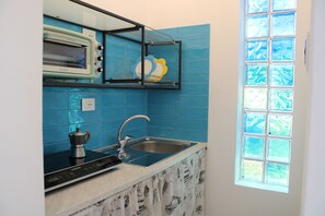 A kitchen with a built-in oven, a sink, and a window with a view of trees. - Le Barchette 9 - Primo Piano (Lecce)