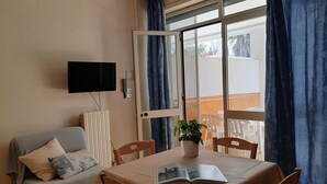 A room with a bed, a TV, a table with a book, and a window with curtains. - Le Barchette 5 - Piano Terra (Lecce)