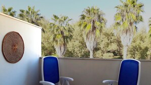 A balcony with two blue chairs, a small table with a bowl of cereal and two glasses of orange juice, and a woven wall hanging. - Le Barchette 11 - Primo Piano (Lecce)