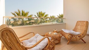 A balcony with wicker furniture, a table with a teapot and cup, and a view of palm trees. - Residenza Excelsior 706 (Vasto)