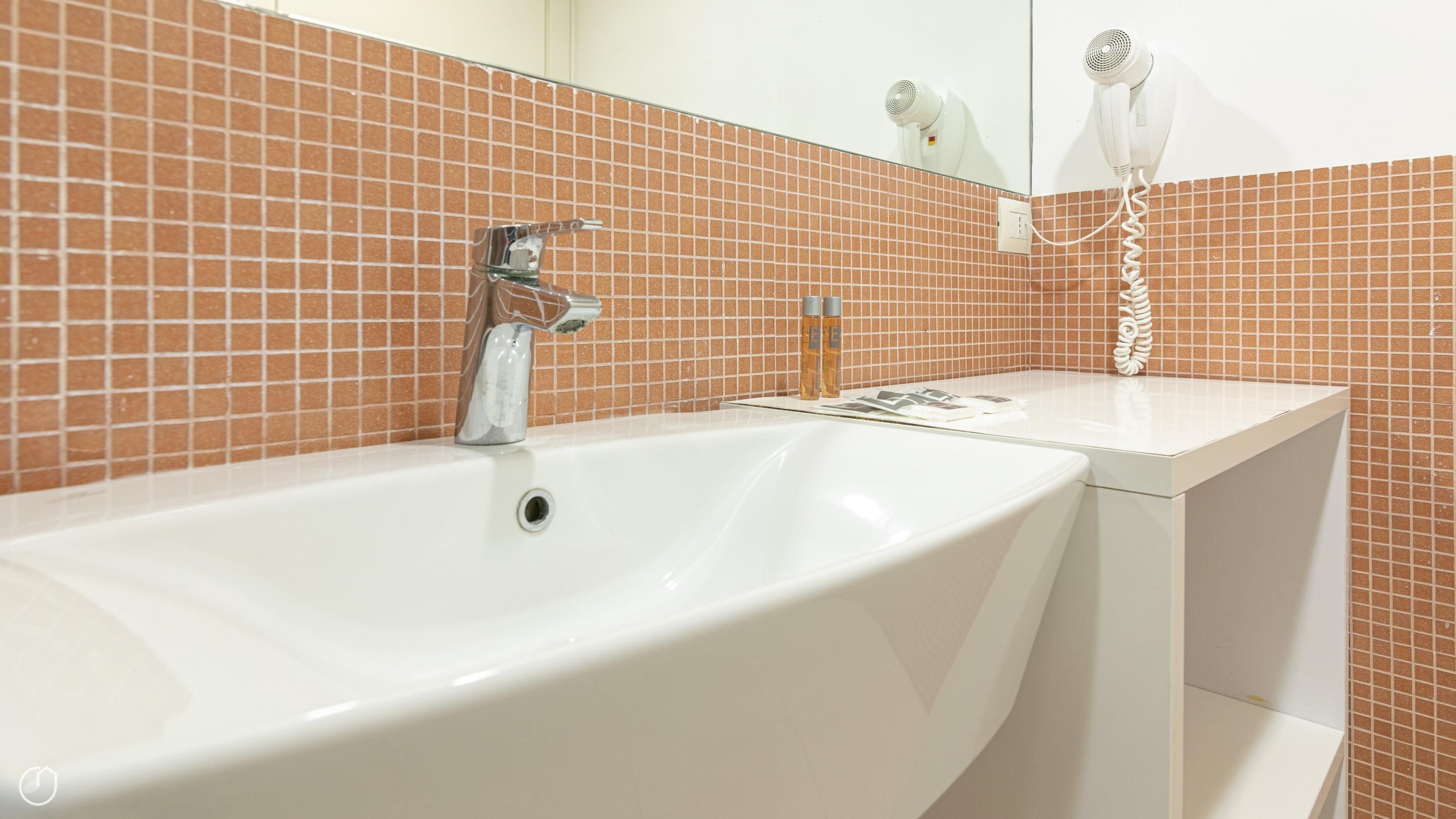 A bathroom with a white sink, a chrome faucet, and a mirror above it.