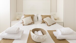A neatly made bed with white linens, two beige pillows, and a woven basket with towels. - Residenza Excelsior 705 (Vasto)