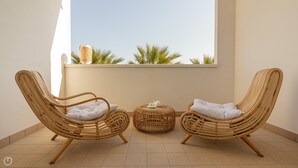 Two wicker chairs with cushions, a small round table with a teapot and cup, and a view of palm trees through a window. - Residenza Excelsior 705 (Vasto)