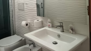 A bathroom with a white sink, a bidet, a toilet, and a mirror. - Le Barchette 12 - Primo Piano (Lecce)