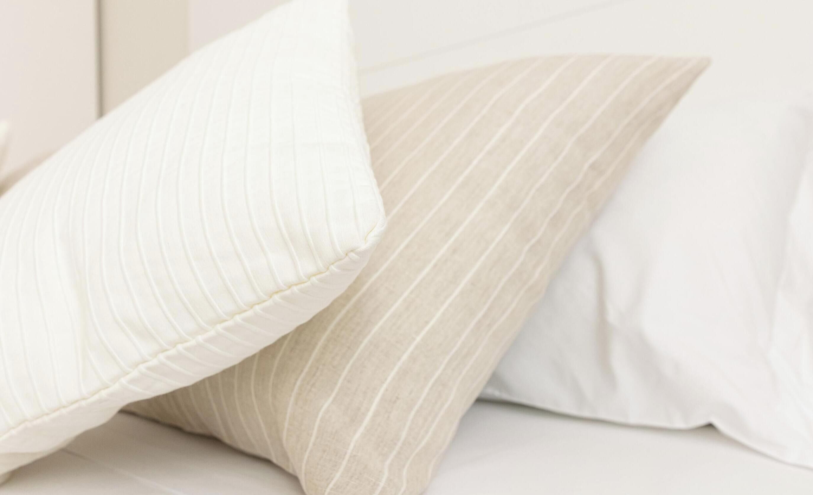 A close-up of two pillows with ribbed and striped patterns on a bed.