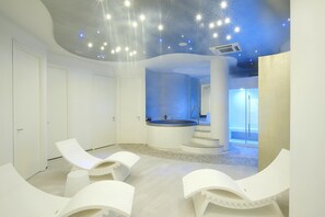 A modern spa room with a central hot tub, white lounge chairs, and a ceiling with star-like lights. - Residenza Excelsior 707 (Vasto)
