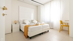 A modern hotel room with a large bed, bedside tables, a desk, and a chair. - Residenza Excelsior 707 (Vasto)
