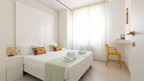 Une chambre d’hôtel avec un grand lit, une table de chevet, une chaise et une fenêtre avec des rideaux.