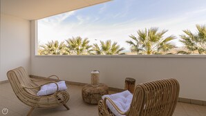 A balcony with wicker furniture, a small table, and a view of palm trees. - Residenza Excelsior 704 (Vasto)