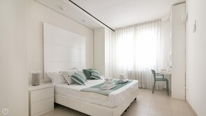 A modern bedroom with a large bed, a desk, and a chair. - Residenza Excelsior 701 (Vasto)