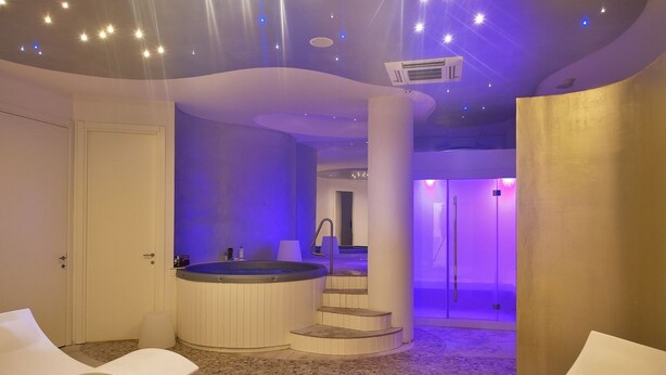 Moderni spa-alue, jossa on poreallas, aurinkotuoleja ja portaikko, joka johtaa yksityiseen huoneeseen.