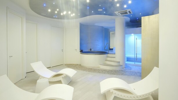 A modern spa room with a central hot tub, white lounge chairs, and a unique ceiling design with star-like lights. - Residenza Excelsior 606 (Vasto)