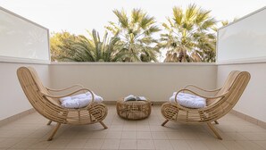 A balcony with two wicker chairs, a small round ottoman, and a book. - Residenza Excelsior 606 (Vasto)