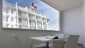 Una camera d'hotel con un balcone, un tavolo bianco e quattro sedie.