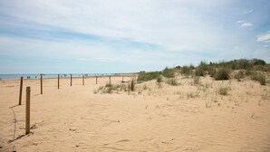 Une plage de sable avec une clôture en bois et des dunes en arrière-plan.