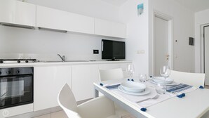 Une cuisine moderne avec des meubles blancs, un four encastré et un four à micro-ondes.