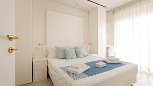 A modern hotel room with a large bed, a bedside table with a lamp, and a view of the outside through sheer curtains. - Residenza Excelsior 804 (Vasto)