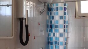 A bathroom with a white sink, two toilets, a shower with a blue checkered curtain, and a window. - Le Barchette 8 - Primo Piano (Lecce)