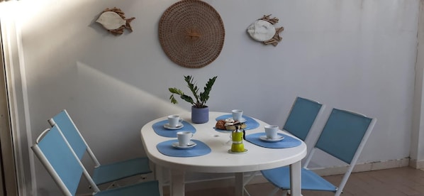 A round table with four chairs, a potted plant, and a coffee machine.