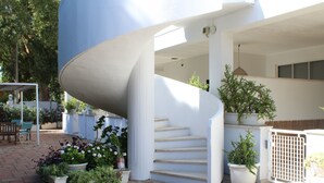 Un escalier en colimaçon mène à un espace extérieur abrité, agrémenté de plantes en pot et d’un coin salon.