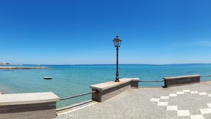 Une promenade en bord de mer offrant une vue dégagée sur l’océan, un phare visible au loin et un pavé aux motifs décoratifs.